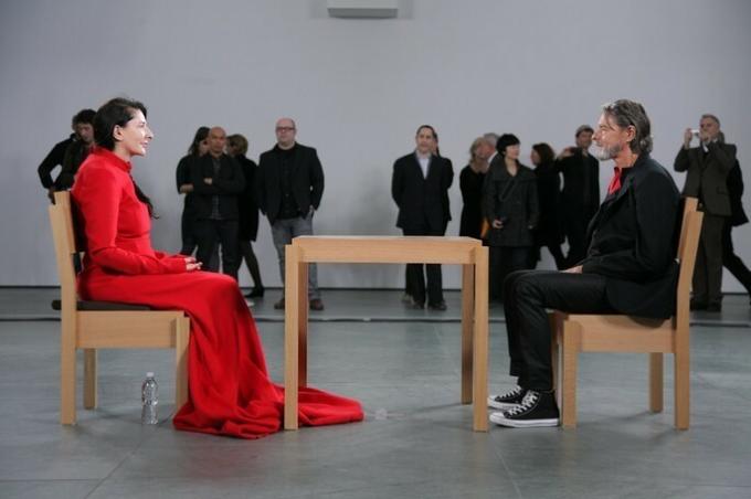 Mulher with vermelho dress and homem from roupa escura sitting face to face