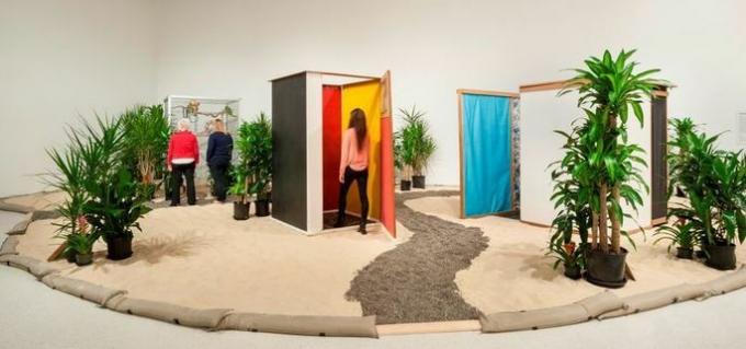 work Tropicália, by Hélio Oiticica shows installation with colorful walls, paths of stones and plants