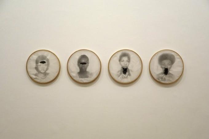 Work of Rosana Paulino exhibiting images of black women with embroidered pretos in mouths, eyes and throat